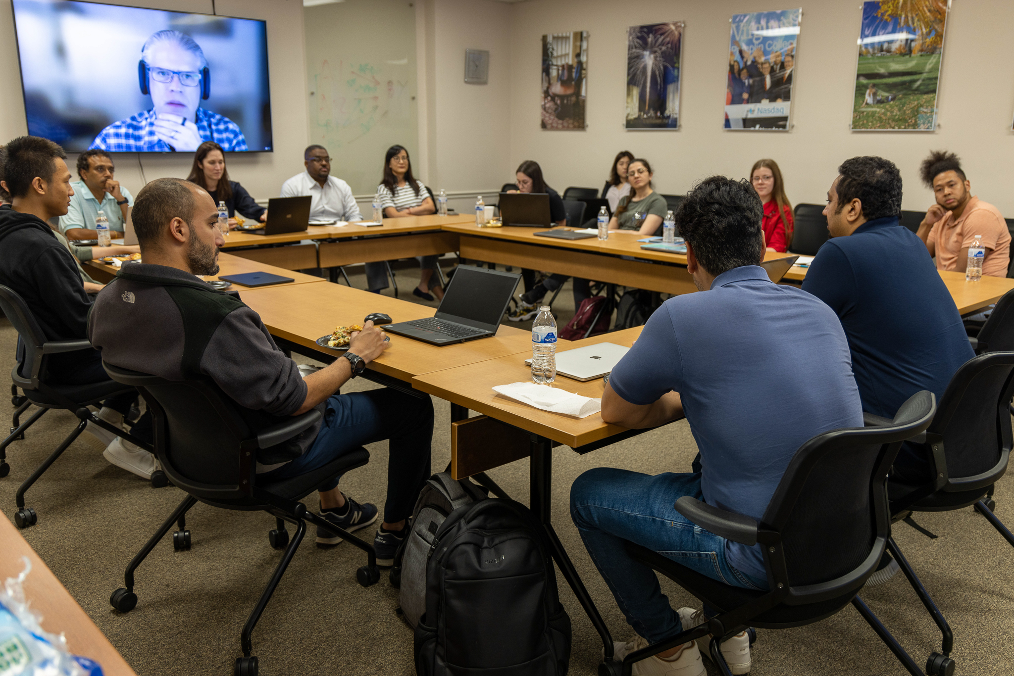 Exterior architecture with sunlit glass façade and people gathering outside Academic Building One