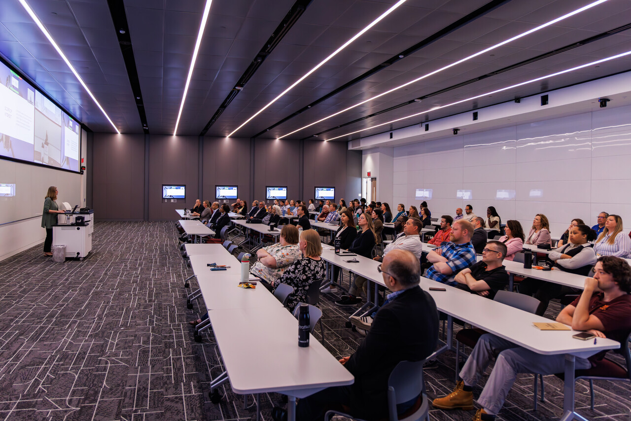Man types on a laptop next to a code-filled wall display